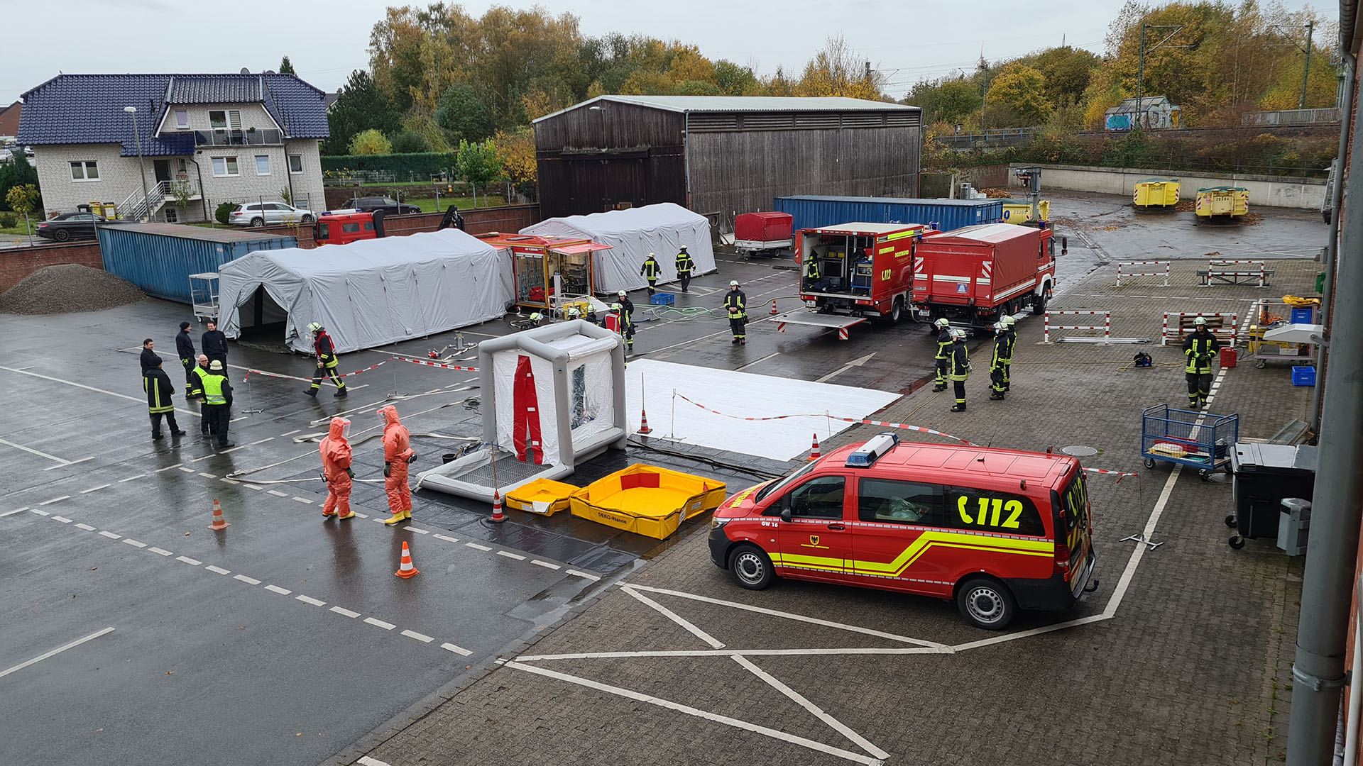 Feuerwehrfahrzeuge und aufgebauter Dekontaminationsplatz mit Duschzelten und Einpersonendusche zur Dekontatmination von Einsatzkräften