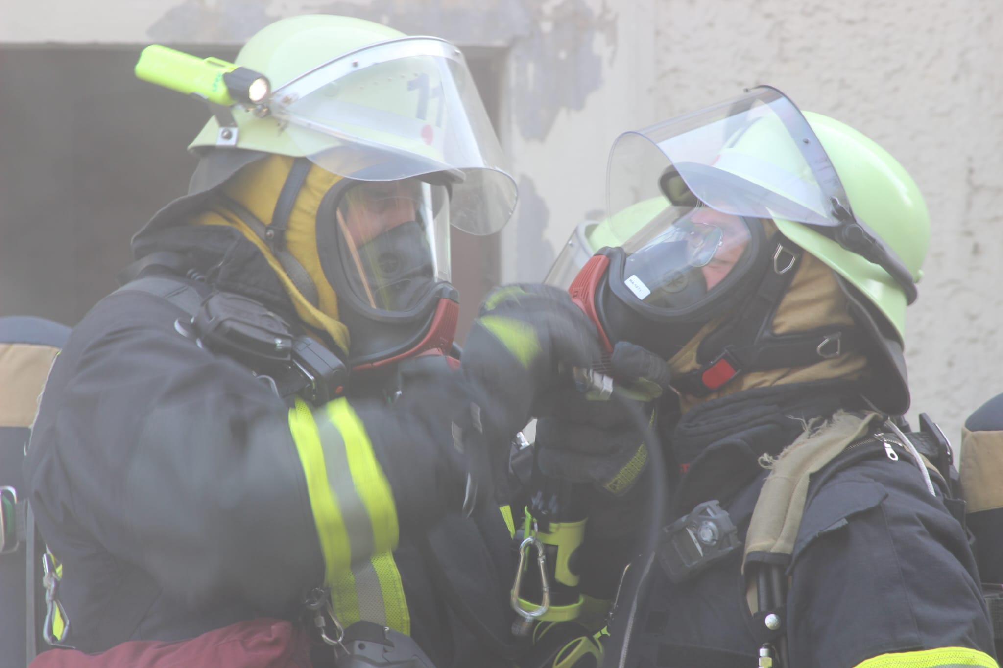 Feuerwehrleute schließen sich gegenseitig das Atemschutzgerät an
