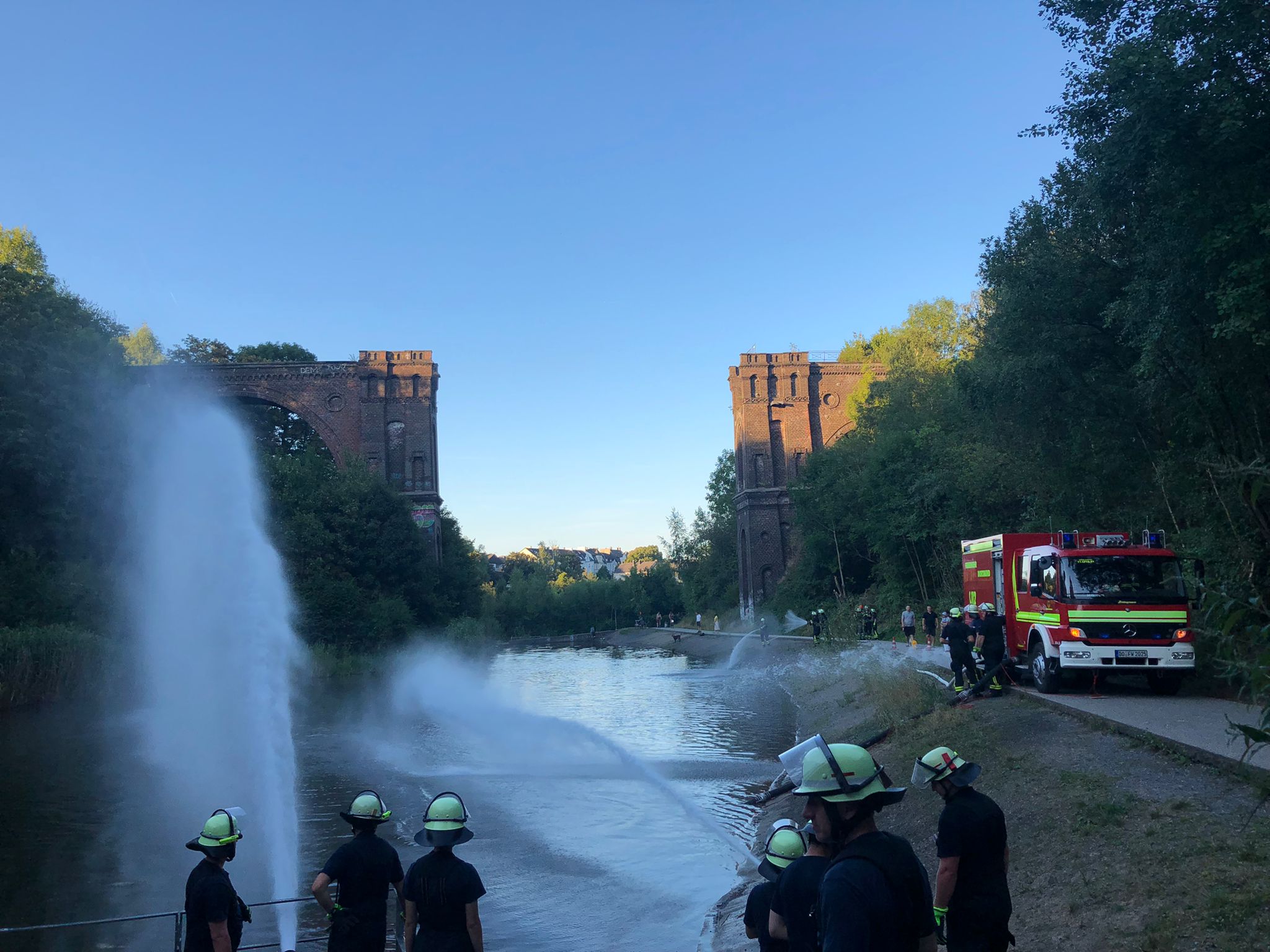 Feuerwehrleute üben unter einer Brücke offene Wasserentnahme